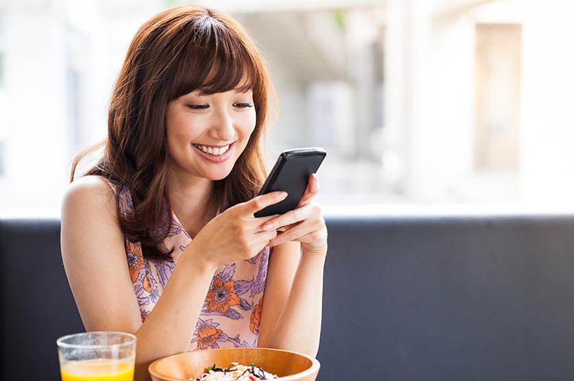 A woman reads on her phone over lunch